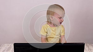 Little caucasian girl blonde looks into the laptop computer, female, childhood