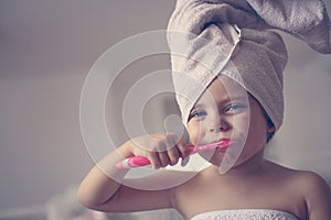 Little Caucasian girl brush her teeth in the bathroom.