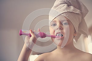 Little Caucasian girl brush her teeth in the bathroom.