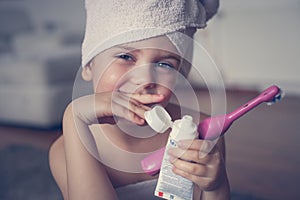Little Caucasian girl brush her teeth in the bathroom.