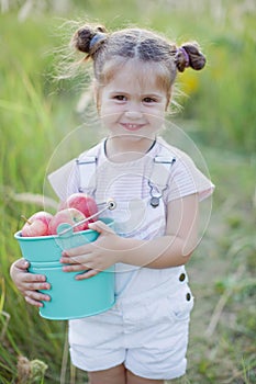 Little caucasian girl with bucket of apples