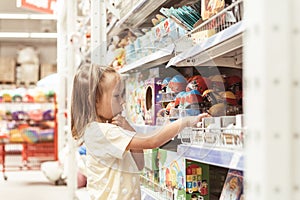 Little caucasian girl choosing a new toy in the big baby store