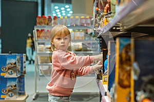 Little caucasian girl coosing a new toy in the big baby store