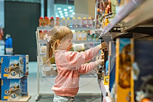 Little caucasian girl coosing a new toy in the big baby store