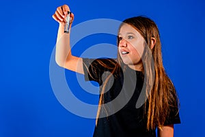 Little caucasian girl holding an hourglass over blue estudio background