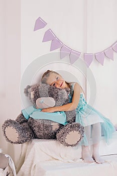 little caucasian girl hugs big gray teddy bear