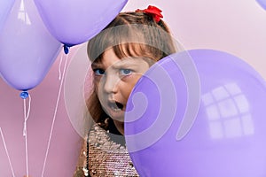 Little caucasian girl kid holding balloons clueless and confused expression