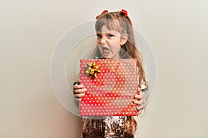 Little caucasian girl kid holding red gift clueless and confused expression