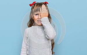 Little caucasian girl kid wearing casual clothes covering one eye with hand, confident smile on face and surprise emotion