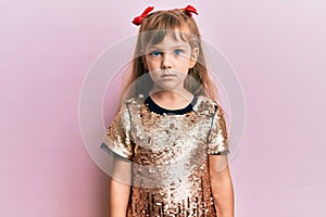 Little caucasian girl kid wearing festive sequins dress relaxed with serious expression on face