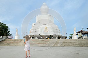 Little caucasian girl looking at white statue of Buddha in Phuket.