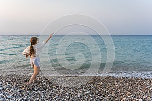 Little Caucasian girl running on the beach to the blue sky with sunset