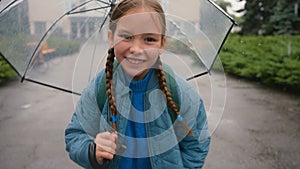 Little Caucasian girl running smiling rain holding umbrella school street city outside happy child walking park funny