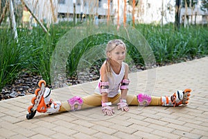 A little caucasian girl sits in a transverse twine shod in roller skates.