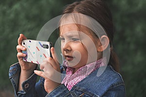 Little Caucasian girl taking pictures on her smartphone photo camera