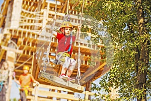 Little caucasian girl using a zip line in a rope playground structure.