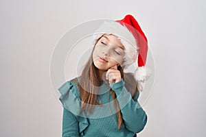 Little caucasian girl wearing christmas hat thinking concentrated about doubt with finger on chin and looking up wondering