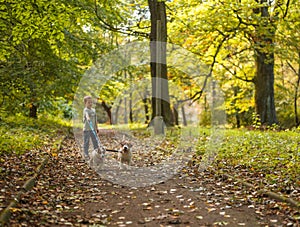 Little caucasian kids running around the autumn park with the dogs.