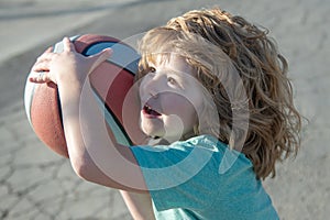 Little caucasian sports kid playing basketball holding ball with funny face.