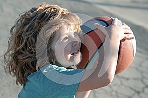 Little caucasian sports kid playing basketball holding ball with funny face.