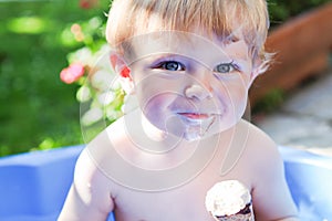 Little caucasian toddler boy eating ice cream in cone