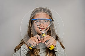 Little charming baby girl in safety glasses with two screwdrivers