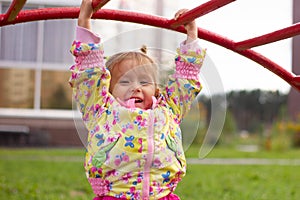 Little charming girl plays in the playground, climbs the stairs