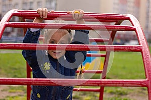 Little charming girl plays in the playground, climbs the stairs