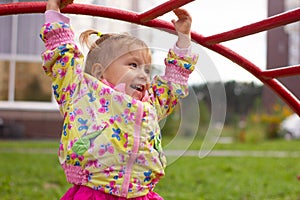Little charming girl plays in the playground, climbs the stairs