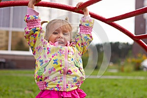 Little charming girl plays in the playground, climbs the stairs