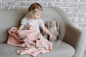 Little charming girl sits on a gray sofa