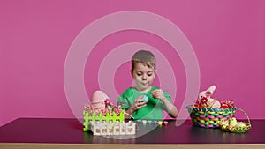 Little cheerful boy crafting handmade easter decorations by painting