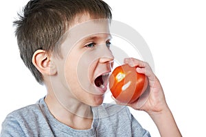 Little cheerful boy eating tomato isolated