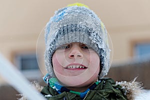 Little cheerful boy playing with snow