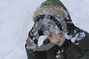 Little cheerful boy playing with snow