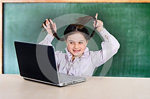 little cheerful girl in glasses with a computer laptop. Science, school, entertainment. online training, games