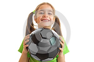 Little cheerful girl in green uniform playing with soccer ball