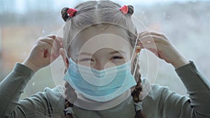 Little cheerful girl putting on surgical mask for corona virus prevention