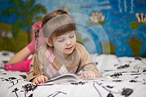 Little cheerful girl read book in bed