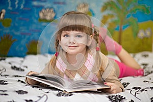 Little cheerful girl read book in bed