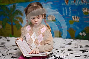 Little cheerful girl read book in bed