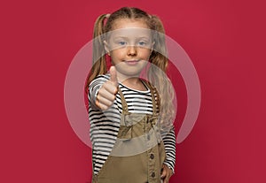 Little cheerful girl shows thumbs up.