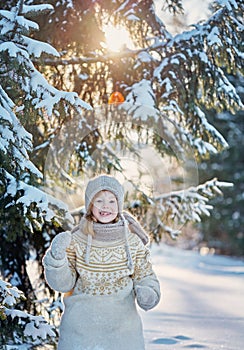 Little cheerful girl in the snowy woods. Sunny winter day