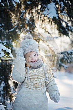Little cheerful girl in the snowy woods. Sunny winter day