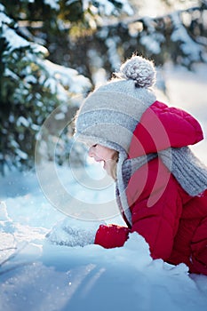 Little cheerful girl in the snowy woods. Sunny winter day