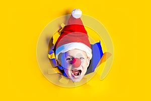 Little cheerful Santa in hat smiles, getting out of the ragged yellow background lit by neon light