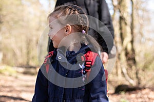 Little cheerful smiling girl looks away. Child on a walk in the park