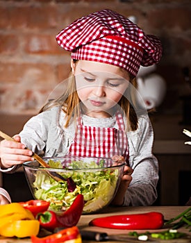 Little chef girl mixing salad