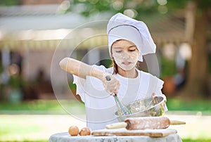 Little chef whipping eggs in a bowl outdoors