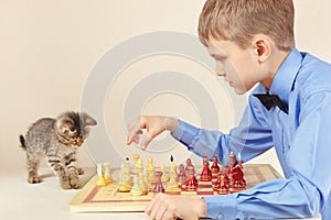 Little chessplayer with cute kitten plays chess.